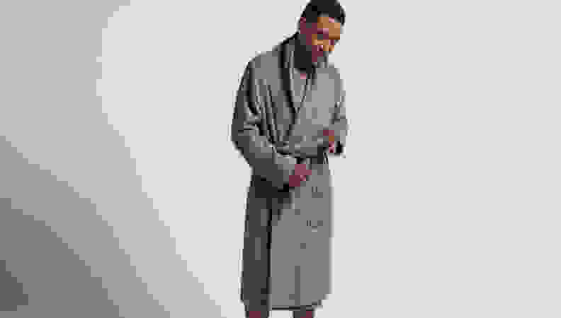Man in knee length gray robe on a gray background.