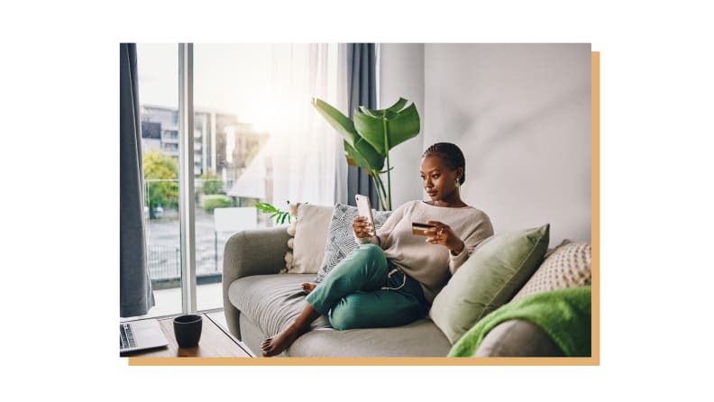 Person sitting on couch indoors while looking at smartphone.