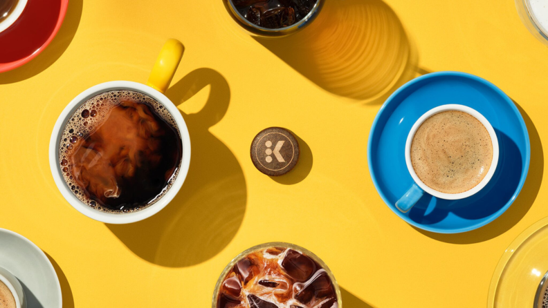 Several cups of hot and iced coffee surrounding a singular K-Round pod