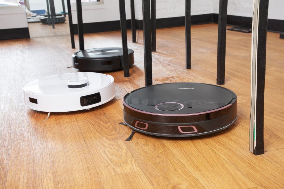 Three robot vacuums on a wood floor dodge table legs