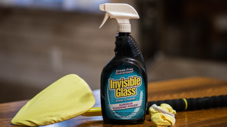 A bottle of glass cleaner stands on a counter with a cleaning tool
