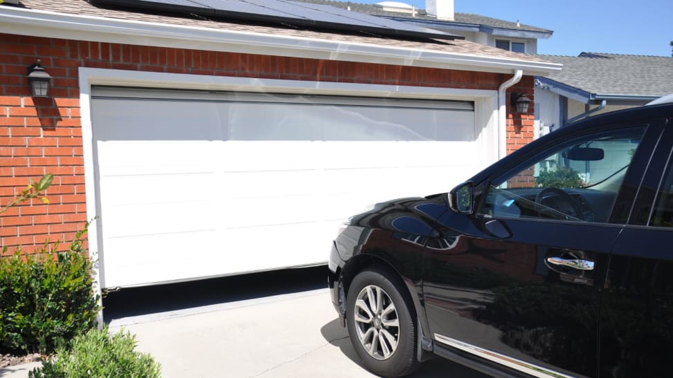 A car parked outside of a residential garage door that is closed