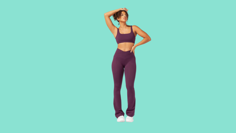 A model wearing a sports bra and matching flared exercise pants in plum.