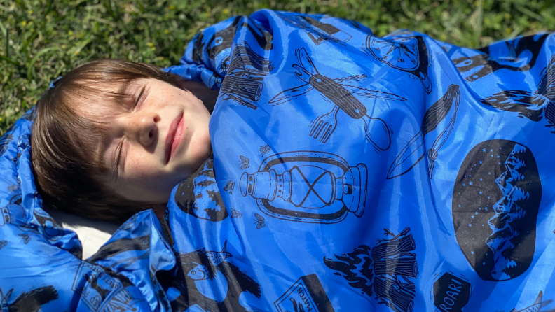 A child smiles in an ANJ Outdoors sleeping bag