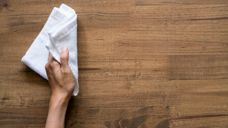 A person cleans a wooden table.