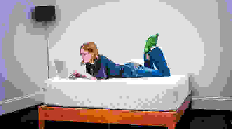 Woman lying on Leesa mattress on her laptop