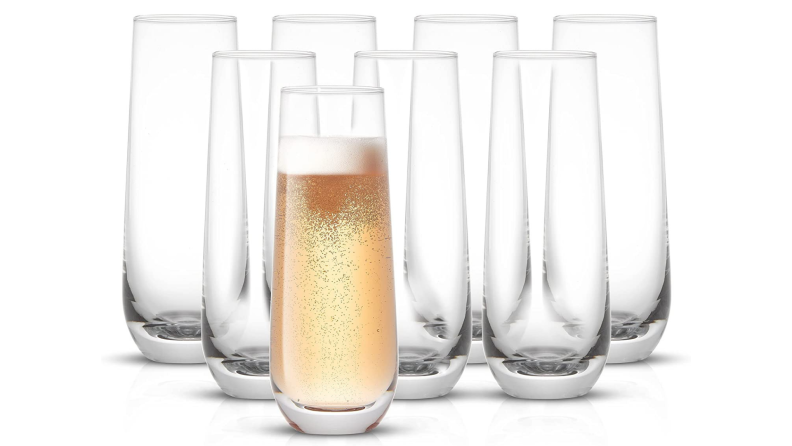 A set of stemless champagne flutes, one of which is filled with champagne