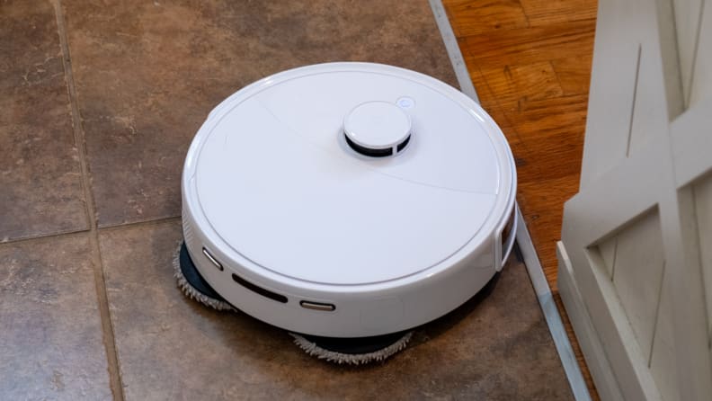 A round robot vacuum on a tile floor