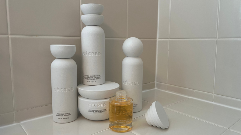 Five bottles of Cécred haircare products on a tiled counter.