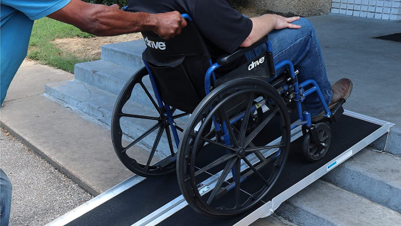 A person utilizes a portable ramp while using a wheelchair.