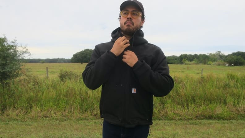 Man adjusting zipper on Carhartt jacket.