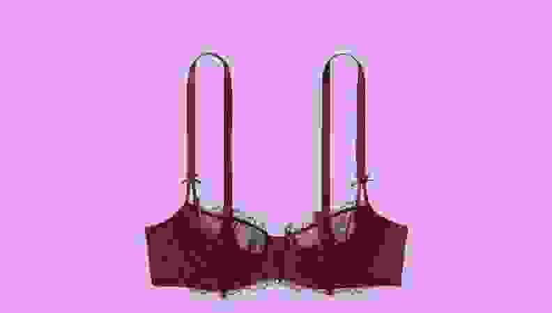 A burgundy bra against a hot pink background.