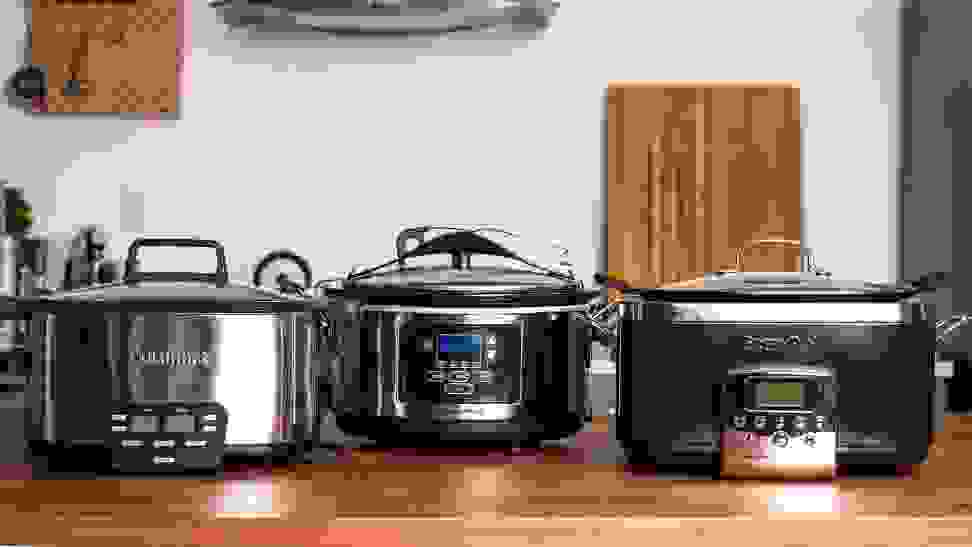 Three of the best slow cookers we tested (Cuisinart, Hamilton Beach, and GreenPan) are displayed on a kitchen counter.