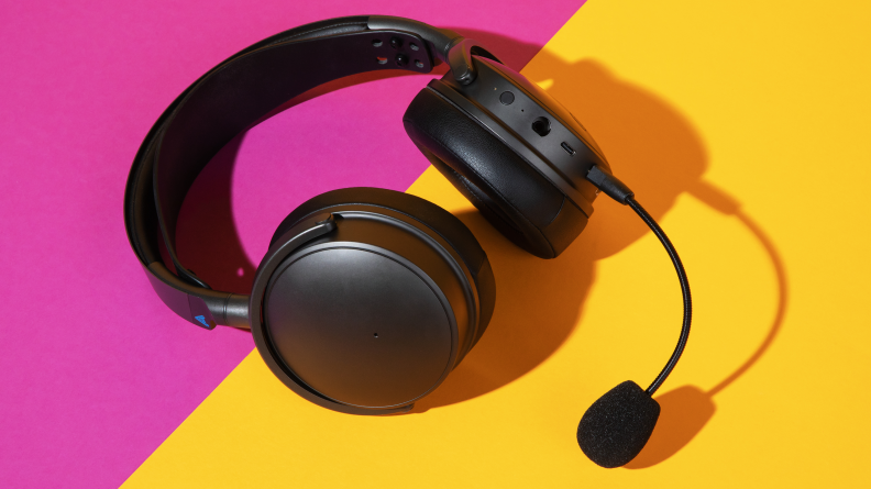 A black pair of headphones against a pink and yellow background