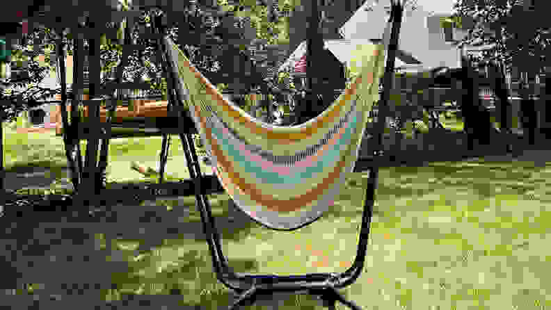 A colorful knitted Yellow Leaf Vista Hammock outdoors on a sunny day.