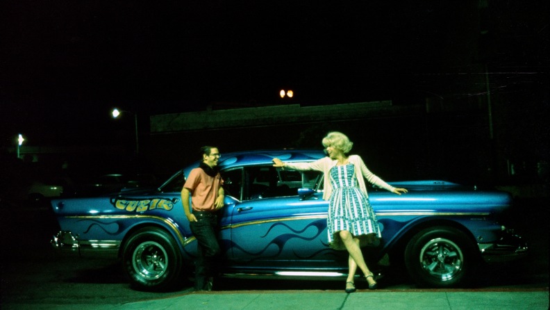 A couple of high-school seniors flirt beside a large blue car in the George Lucas film American Graffiti.