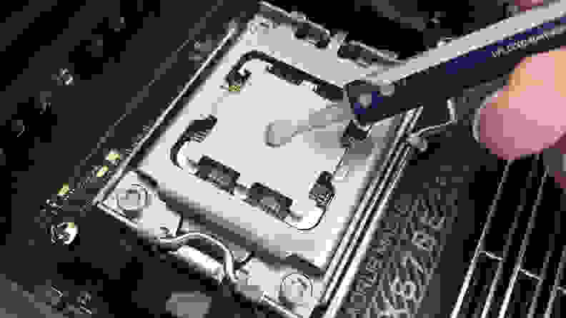 Applying a gray thermal paste onto the top of a computer processor