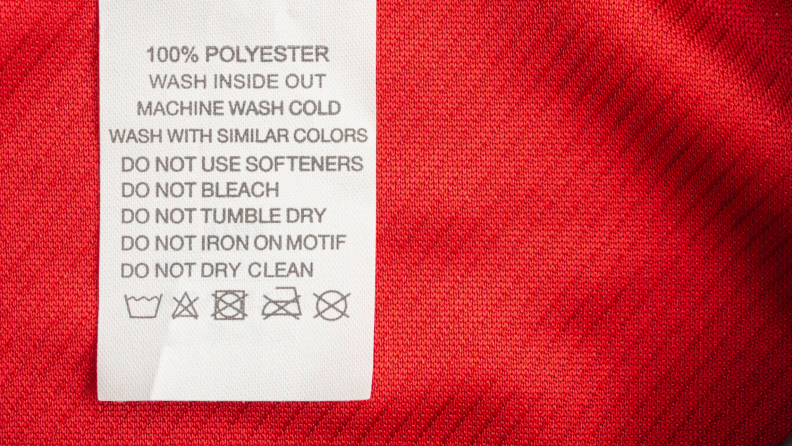Tag on red shirt with laundry care labels and symbols
