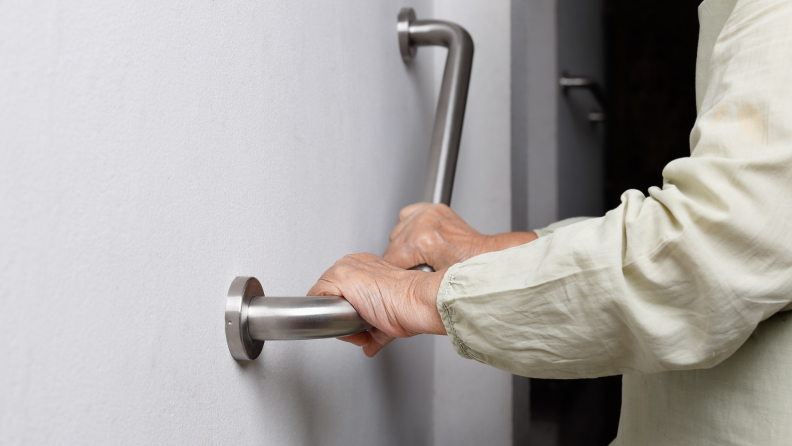 A person holds onto a grab bar inside their home.