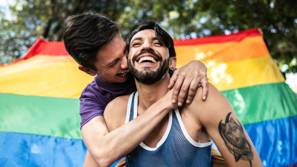 Gay couple kissing in front of a pride flag