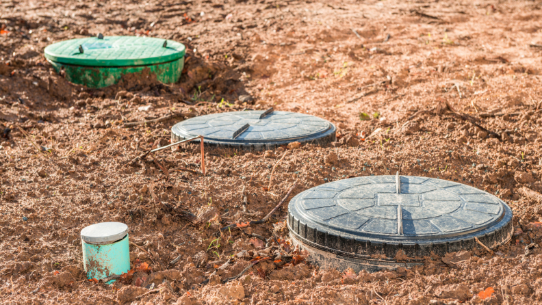 Three septic tank covers in a field.