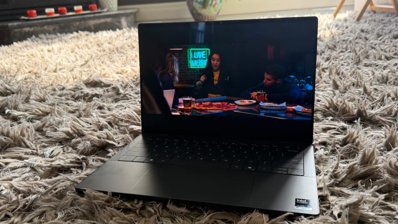 Dell XPS 14 2026 laptop shown streaming a video, sitting on top of a fuzzy gray rug.