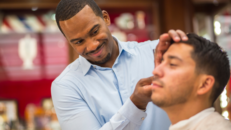 A barber trims his client's hair.