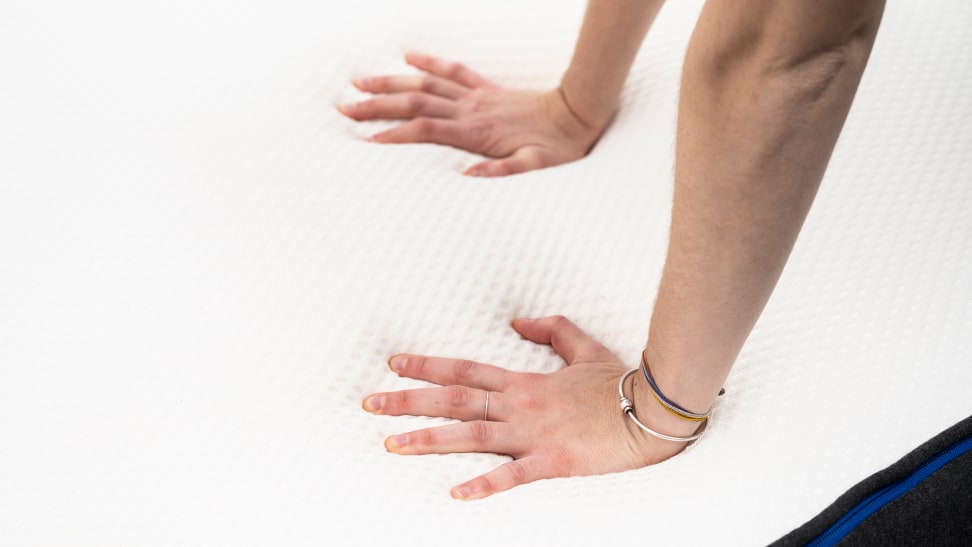 hands pushing down on foam mattress