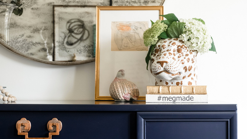 a leopard pot filled with flowers sits on a stack of books with art behind