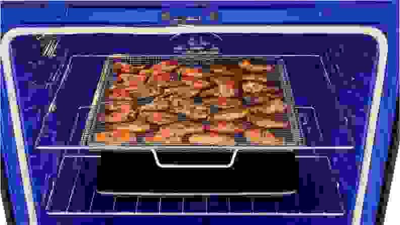 皇家蓝在一个电烤箱里，展示了一张烤盘，里面装满了熟鸡翅。