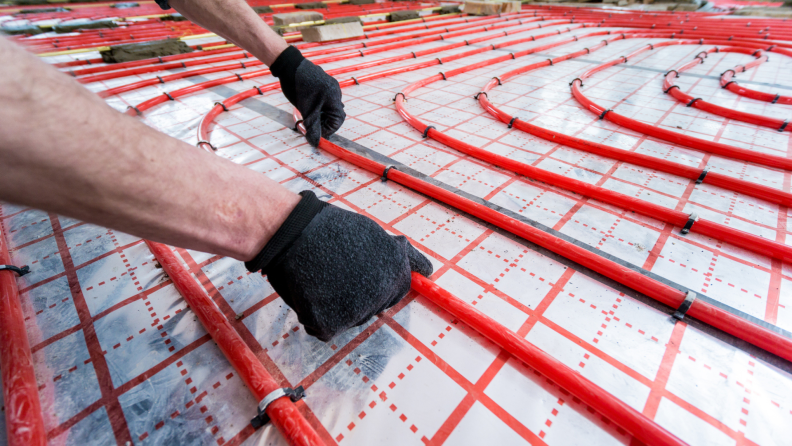 Technician laying pipes on ground for geothermal heating system.