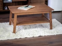 Rectangular white shag rug under wooden coffee table in living room.