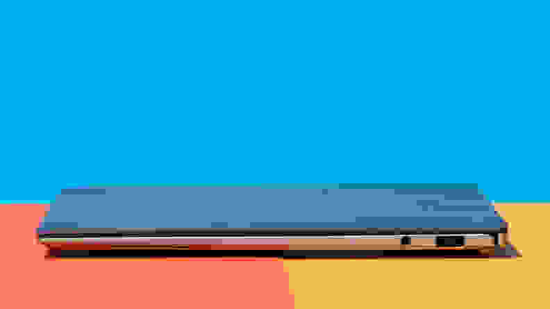 A side-view of a closed laptop aganist a colorful background