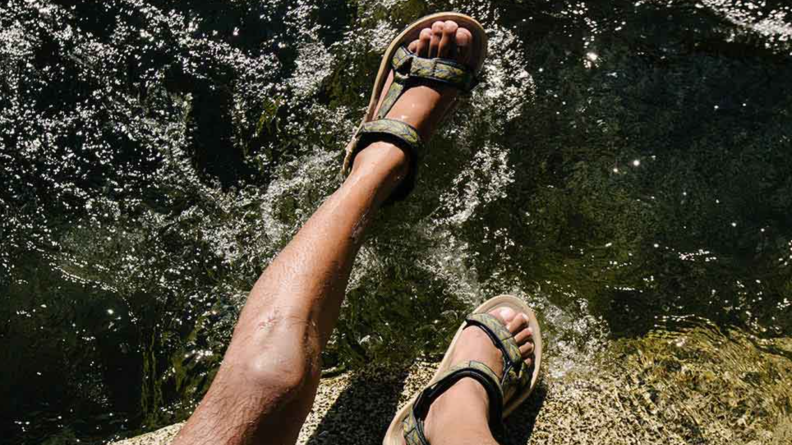 Man wearing Tevas hanging over the water.