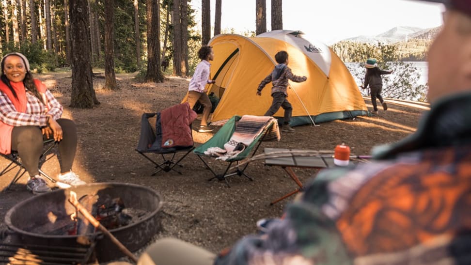 Family around a campfire with a tent in the background