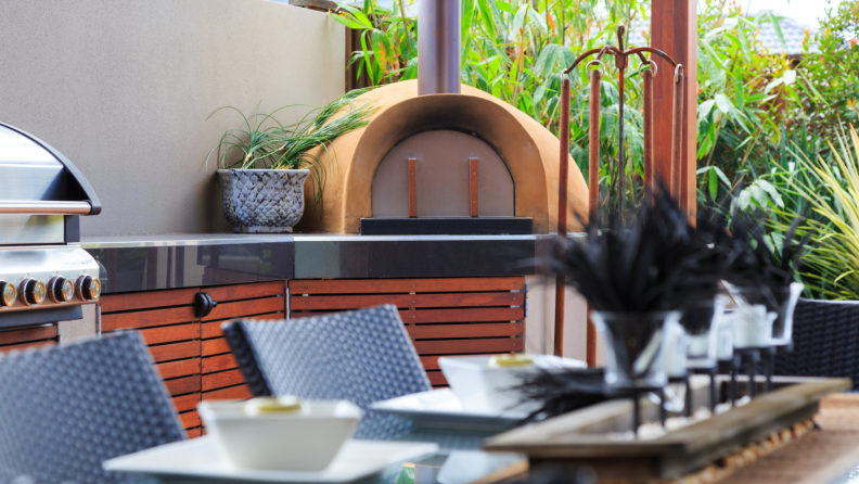 Outdoor kitchen with a pizza oven next to a dining table
