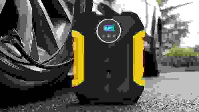 Black and yellow compressor connected to car tire