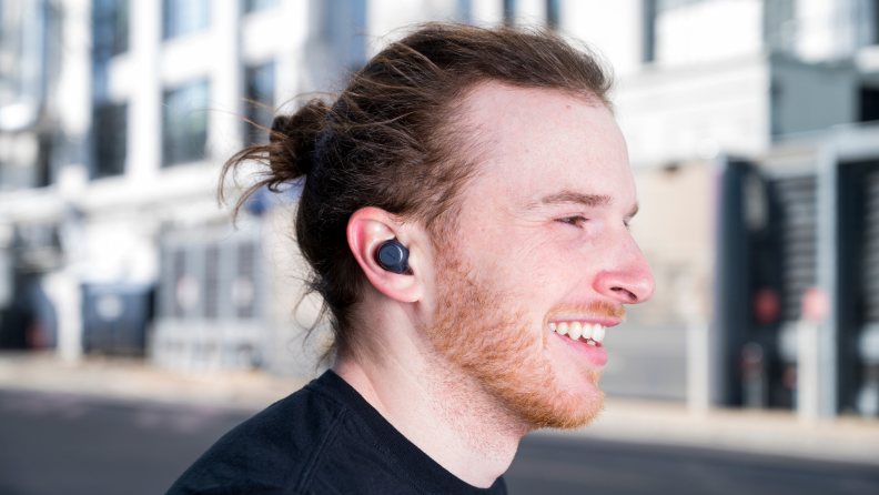 A person wears earbuds outside.