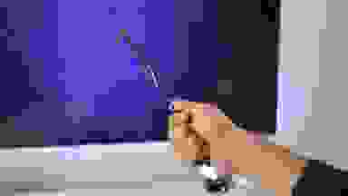 A hand holding out the Harry Potter Magic Wand in front of a TV.