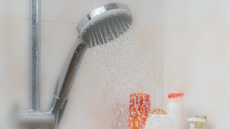 A steamy shower door through which you can see a shower head and products.