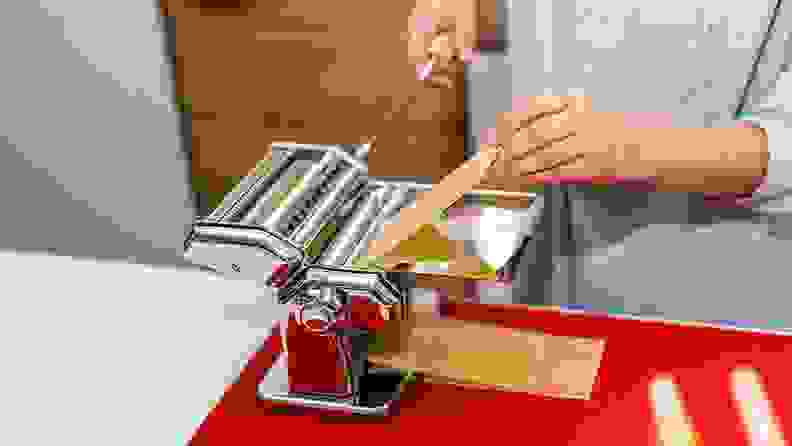 Person using pasta maker on countertop.