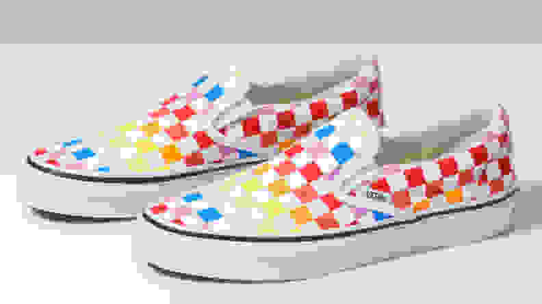 A pair of rainbow, checkered Vans against a white backdrop.