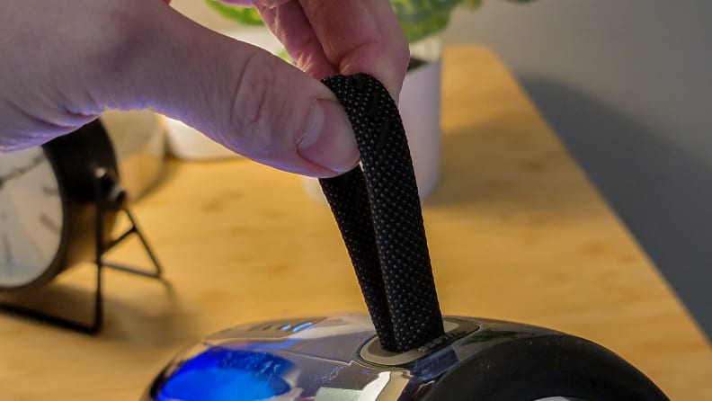 A hand holding up the JBL Pulse 5's carrying strap.