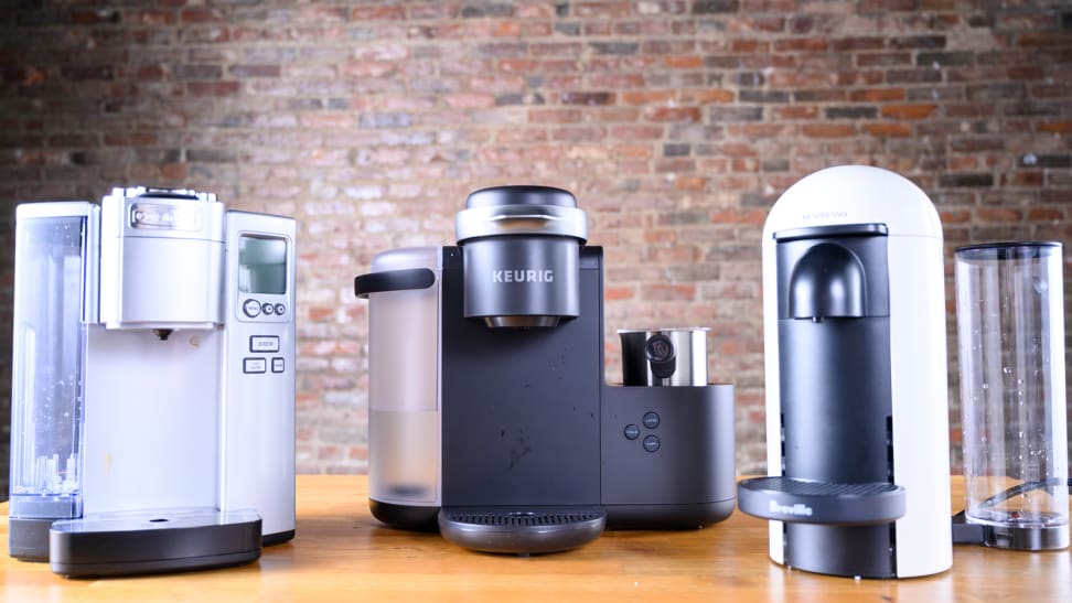 Shown sitting on a table from left to right: The Cuisinart SS-10, Keurig K-Cafe, and Nespresso VertuoPlus by Breville single-serve coffee makers.