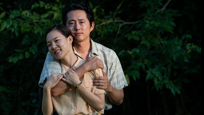 A still from the film Minari with actor Steven Yeun embracing actress Han Ye-ri