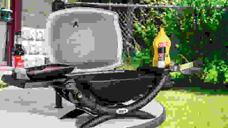 A portable grill on a backyard table.