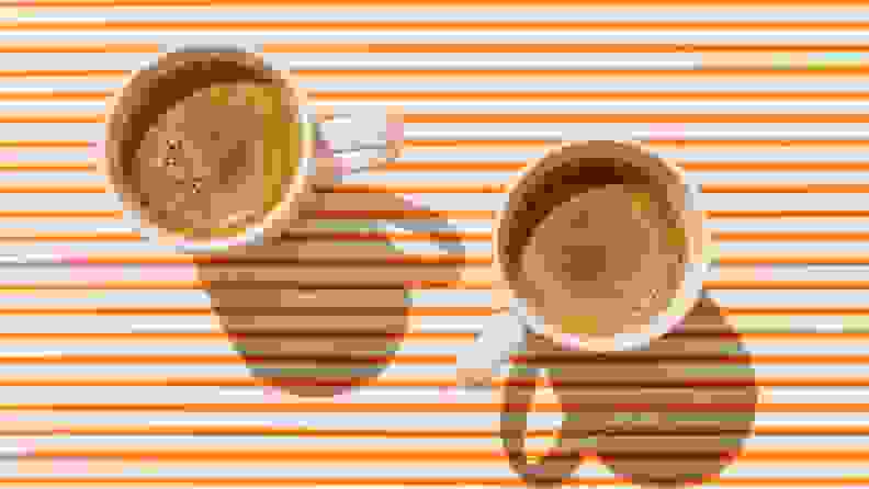 Two cups of coffee on orange striped background