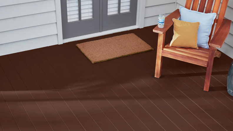 The rich brown of Valspar One-Coat Solid Stain & Sealer applied to a sunny deck with a chair on it.