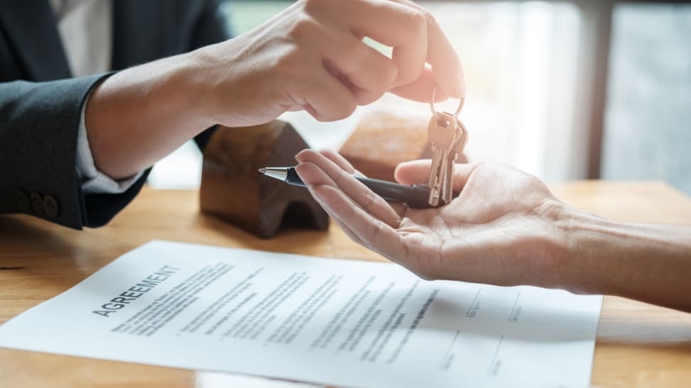 A person handing over a set of keys over a contract