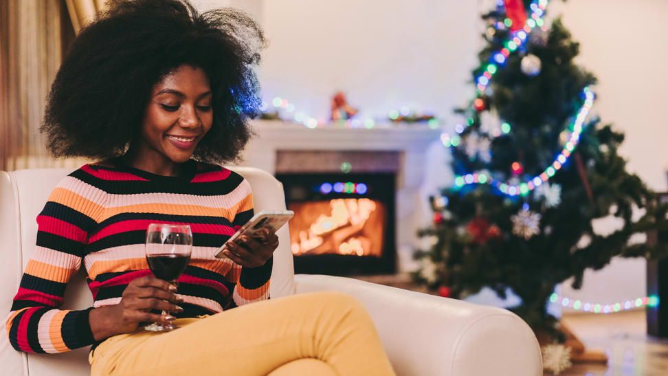 A woman on her phone in front of a Christmas tree